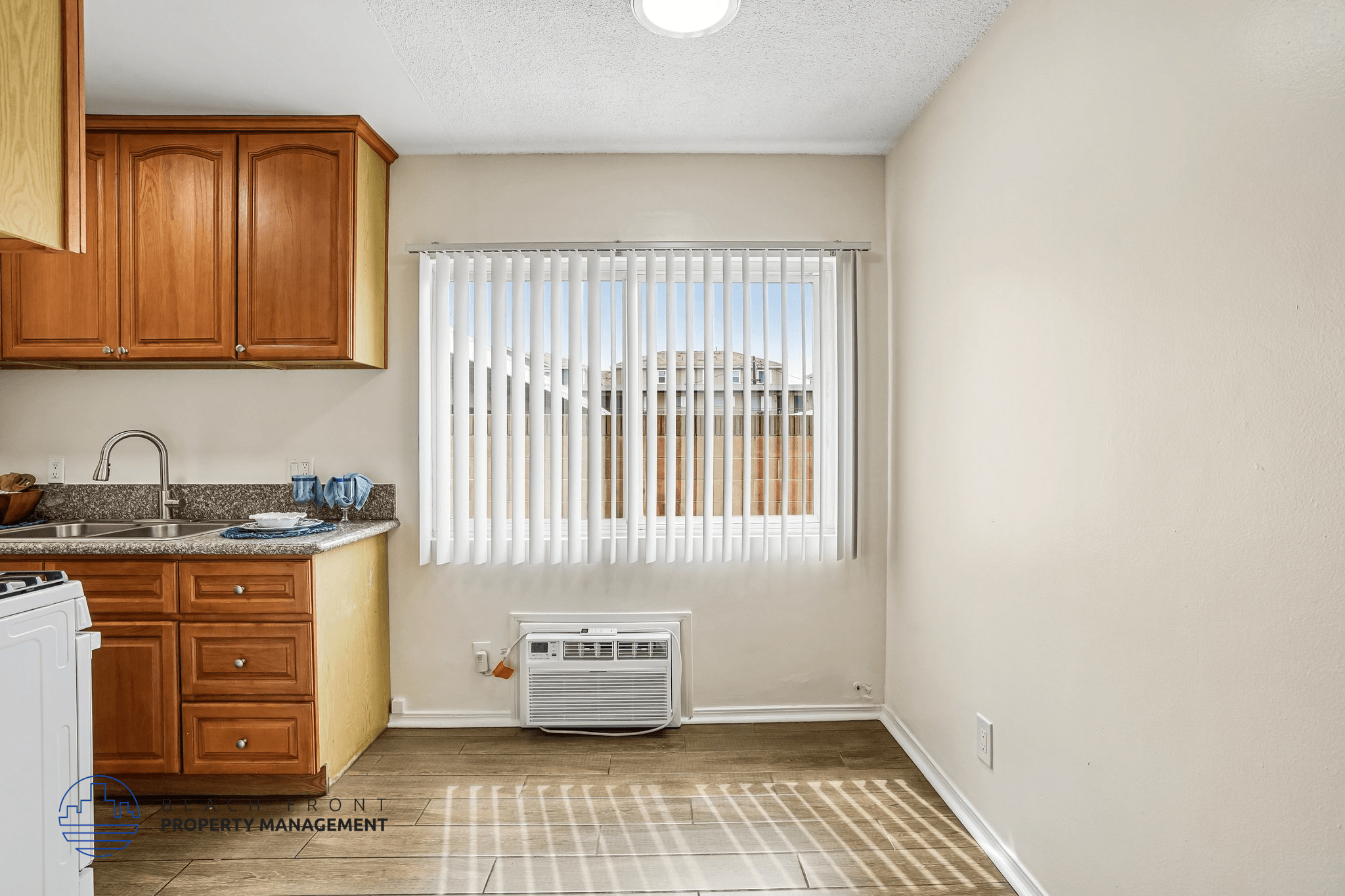 A kitchen with a white fridge, wooden cabinets, and a window with blinds.